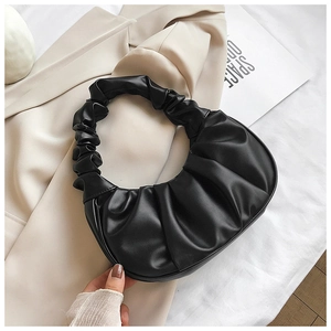 Close-up detail of black pleated leather croissant bag with stylish ruched handle design
