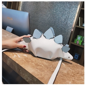 Detail of stegosaurus dinosaur shape handbag with light blue 3D plates and white faux leather