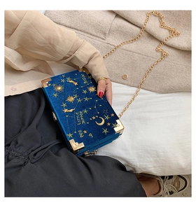 Détail du sac boîte en velours bleu marine avec broderie d'étoiles dorées et chaîne