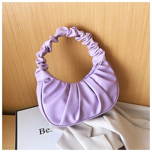 Close-up of light purple pleated dumpling bag on a wooden background with a blazer