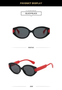Detail of oval vintage sunglasses showing black frames and vibrant red temples