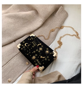 Détail d'un sac boîte en velours noir avec broderie d'étoiles dorées et chaîne en métal