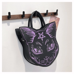 Close-up of gothic cat face handbag with purple print hanging on a wooden wall hook