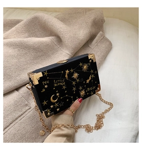 Détails de broderies d'étoiles dorées sur un sac boîte en velours noir avec chaînette