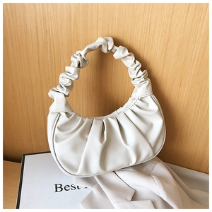 Detail of white pleated cloud bag with scrunchie handle on minimalist display