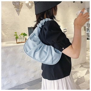 Detail shot of light blue pleated dumpling bag shown on a model in a modern interior