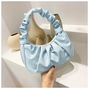 Detail of light blue pleated croissant bag with soft leather texture and stylish handle