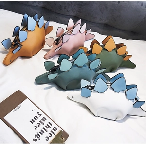 Detailed view of mini dinosaur crossbody bags in various colors and textured PU leather