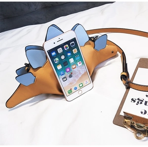 Size reference of yellow dinosaur crossbody phone bag next to a smartphone