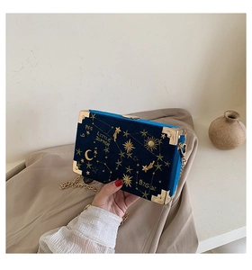 Détails de broderie d'étoiles et lune sur un mini sac boîte en velours bleu