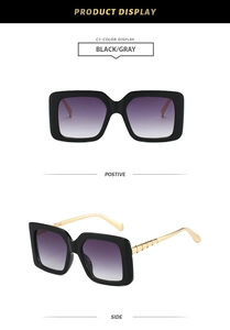 Detail of square oversized black sunglasses featuring gradient purple lenses and gold temples