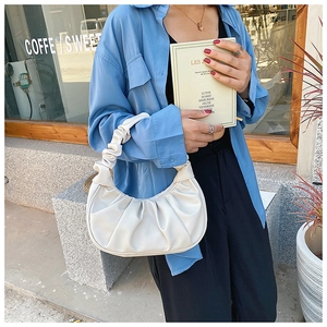 Detail of white pleated moon bag with soft PU material and gathered handle held by model