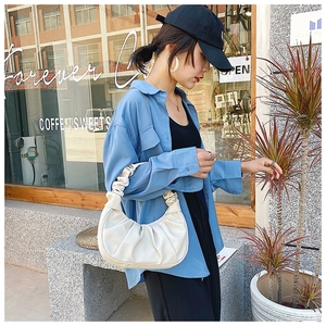Detailed view of the pleated beige dumpling bag texture held by a fashion model