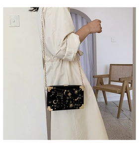 Détail du sac boîte en velours noir avec broderie dorée et bandoulière chaîne