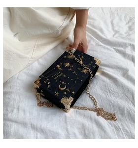Détail du sac boîte en velours bleu marine avec broderie étoilée dorée et chaîne vintage