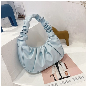 Detail of light blue pleated croissant bag on minimalist white display with decor
