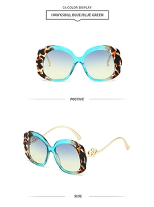 Detail of scalloped tortoiseshell sunglasses with blue-green lenses and gold heart temples