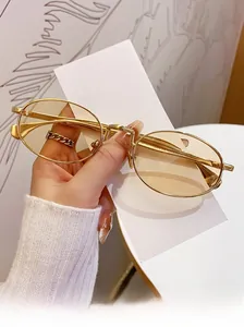 Detail of oval sunglasses with gold metal frames and light brown tinted lenses
