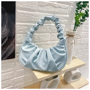 Detail of light blue pleated croissant bag made of premium faux leather on a shelf