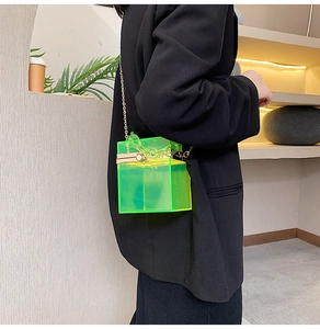 Dettaglio borsa a scatola in acrilico verde neon con catena dorata su blazer nero