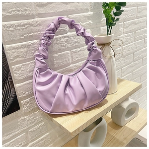 Close-up of a lavender pleated hobo bag with gathered texture on a wooden shelf