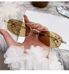 Detail of gold metal oval sunglasses with sparkling rhinestones and cross-star ornaments