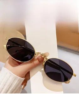 Detail of trendy oval sunglasses with bright golden metal frames and full grey lenses