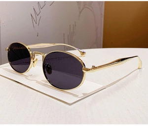 Close-up of golden metal frame sunglasses with dark grey round UV protective lenses