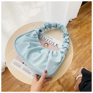 Detail view of sky blue pleated hobo bag with textured PU leather on a wooden table