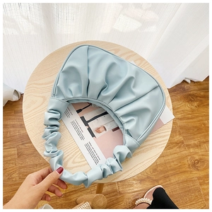 Detail of light blue dumpling bag showing soft pleated handles and PU leather texture