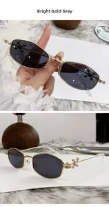 Detail showing bright gold metal frames with rhinestone cross decor and grey lenses