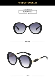 Detail view showing black oversized frame sunglasses with gradient lenses and gold ornaments