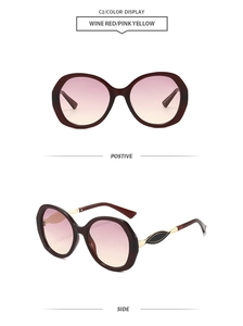 Detail view of wine red oversized sunglasses with pink-yellow gradient lenses and gold temples