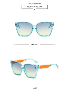 Detail view of square blue sunglasses with blue-yellow gradient lenses and orange temple pads