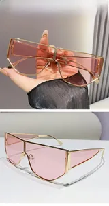 Detail of oversized gold metal sunglasses with transparent pink lenses and geometric edges