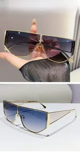 Detail of oversized metal sunglasses with gold frame and blue-to-purple gradient lenses