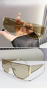 Detail of oversized champagne lenses with geometric gold metal frames and fashion hinges