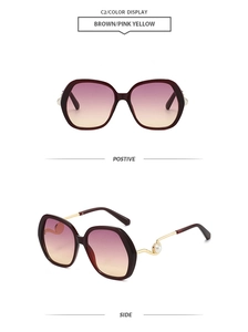 Detail of round burgundy sunglasses with gold wavy temples and decorative pearl tips