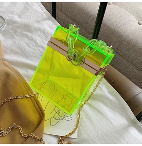Dettaglio borsa a scatola in acrilico verde neon con manico a catena e tracolla oro