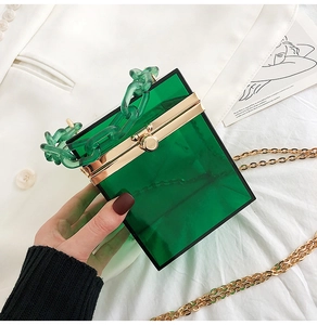 Dettaglio borsa a scatola in acrilico verde con catena spessa e bordo in metallo oro