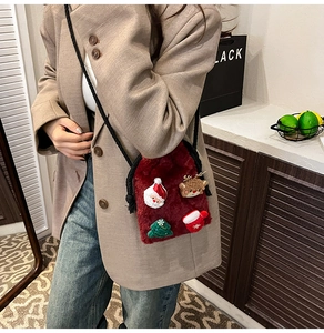 Detail of red plush drawstring bag with Christmas holiday patches and black woven strap