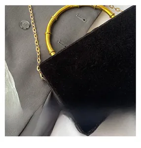 Vue macro détaillée du sac en velours noir avec poignée en métal doré texturé bambou