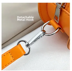 Detail of the detachable silver metal hook and reinforced stitching on the orange pumpkin bag