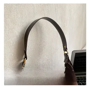 Detail of brown suede hobo bag featuring white contrast stitching and gold metal buckle