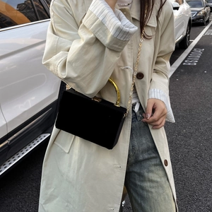 Détail d'un sac boîte en velours noir avec poignée en bambou dorée et chaîne