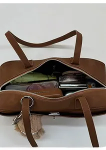 Vista superior del interior del bolso marrón con paraguas, móvil y cosméticos