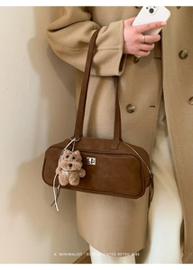 Bolso bowling retro marrón con cierre plateado y colgante de oso sobre abrigo