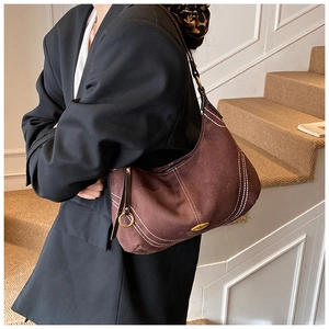 Detail of dark brown suede hobo bag with contrast stitching and golden hardware