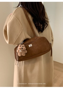 Primer plano de bolso retro marrón con cierre plateado y detalle de colgante de oso