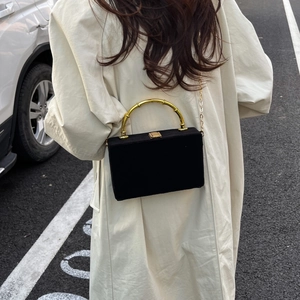 Détail du sac boîte en velours noir avec poignée en bambou doré et bandoulière chaîne